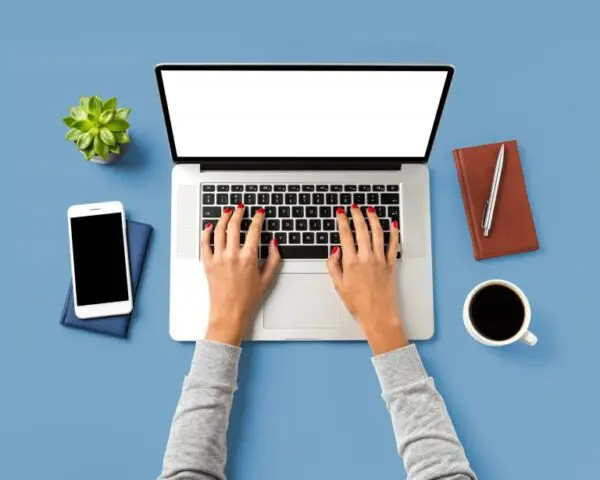 overhead shot of work space with laptop, phone, coffee, and notebook